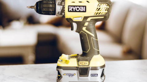 A green and black Ryobi cordless drill on a workbench.